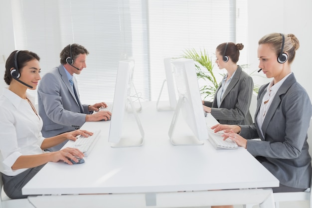 Business team working on computers and wearing headsets