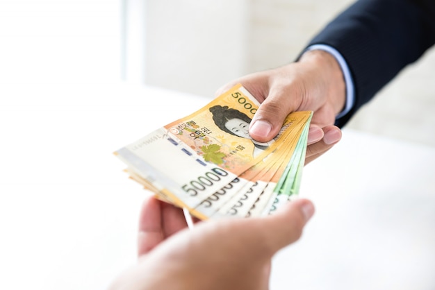 Businessman giving money, South Korean WON currency, to his partner 