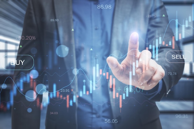 Photo businessman hand pointing at glowing business chart on blurry office interior background trade finance market and financial growth concept double exposure