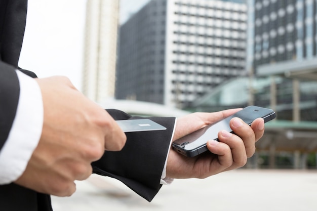 Photo businessman hands holding credit card and using phone.