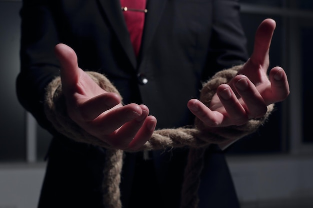 Photo businessman with hands tied in ropes business problems and difficulties