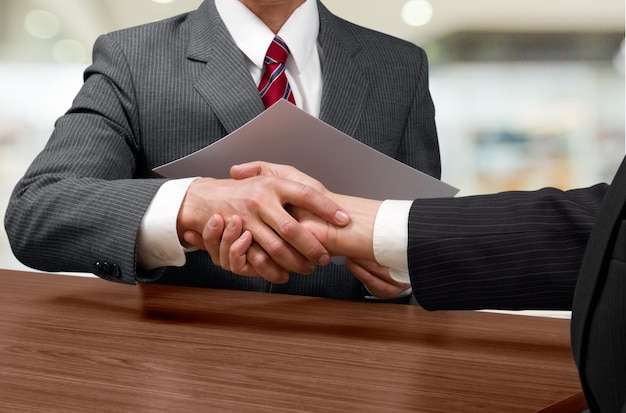 Businesspeople shaking hands white sitting at table