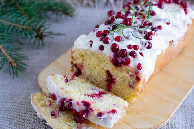 Cake garnished with whipped cream, lingonberries and rosemary sprigs