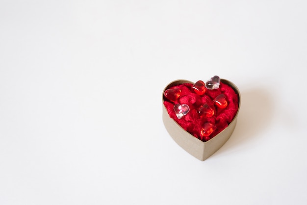 Cardboard box in the form of a heart with red hearts inside on light