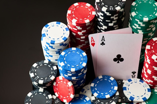 Casino chips and playing cards on dark reflective background