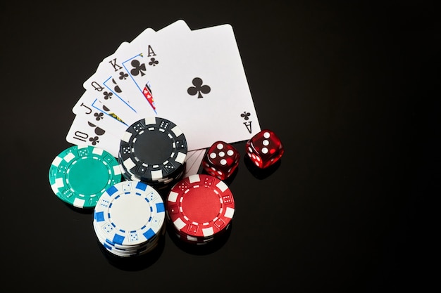 Casino chips playing cards and dices on dark reflective background