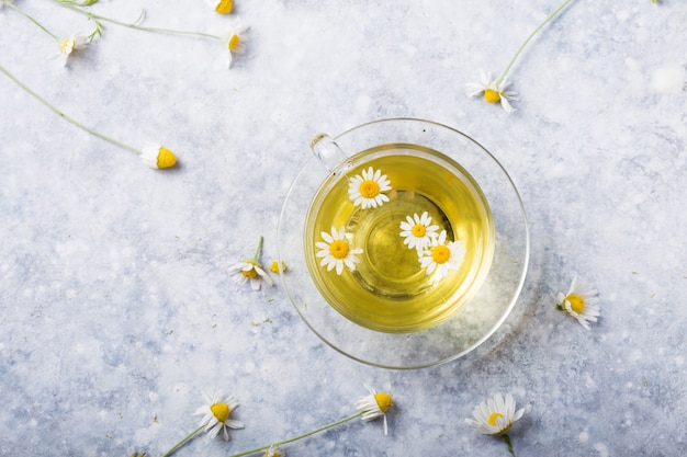 Photo chamomile flowers and chamomile tea in glass teacup