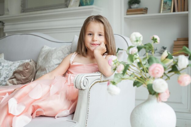 Photo cheerful little child girl in pink dress at home