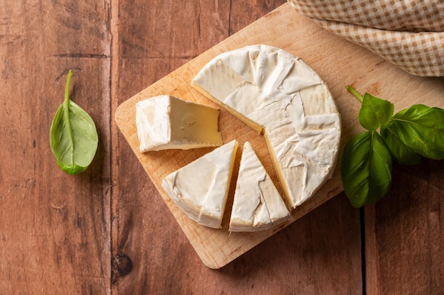 Photo cheese on a cutting board with basil leaves on the side