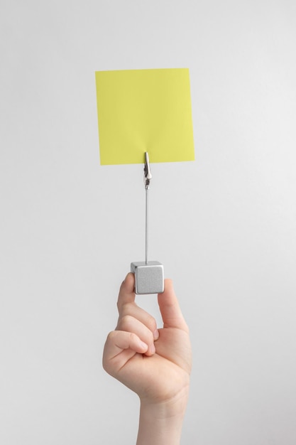 Child hand holding yellow blank reminder or paper notes above a white and gray background copy space