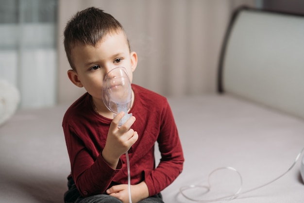 The child sitting on the bed in the bedroom makes an inhalation on their own