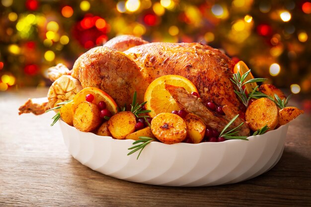 Christmas food. Baked turkey garnished with potato, oranges and  cranberries on a wooden table