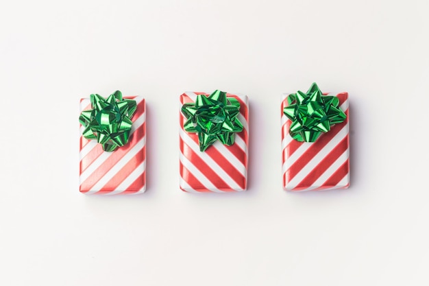 Christmas presents and new year gifts in red striped wrapping paper with green bows on white backgro