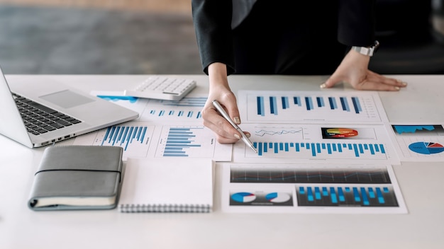 Close-up of a businesswoman hand holding pen pointing at a graph placed on an office table.