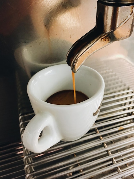 Photo close-up of coffee dripping down into espresso cup