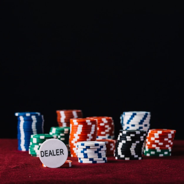 Close-up of dealer and colorful stacked poker chips on red table