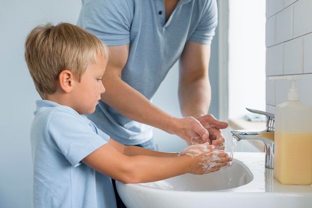 Close-up father teaching son how to wash hands