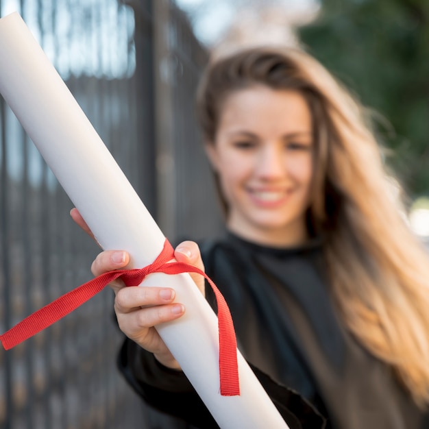 Close-up girl at her graduation holding certificate 