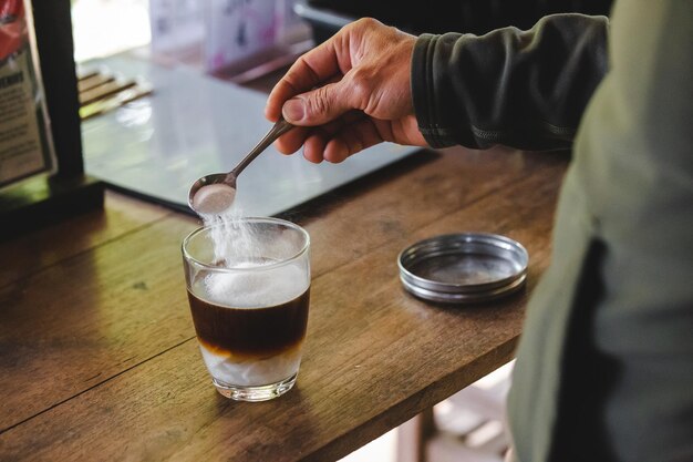 Photo close-up of hand holding coffee cup on table