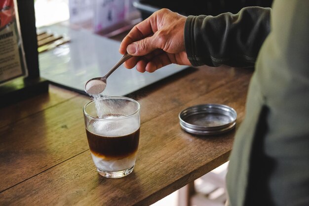 Photo close-up of hand holding drink on table