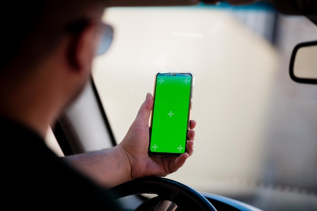 Close up hand man using smartphone with green screen driving car