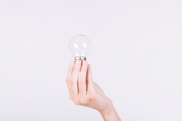 Close-up of a person's hand holding light bulb on white background