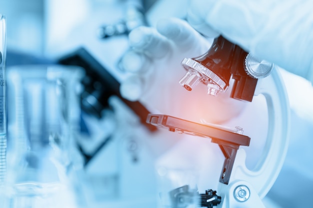 Photo close up scientist using microscope in laboratory room while making medical testing and research