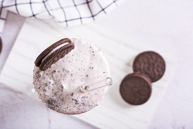 Foto close up van milkshake van chocolade oreo koekjes en ijs in een glas met een rietje bovenaanzicht