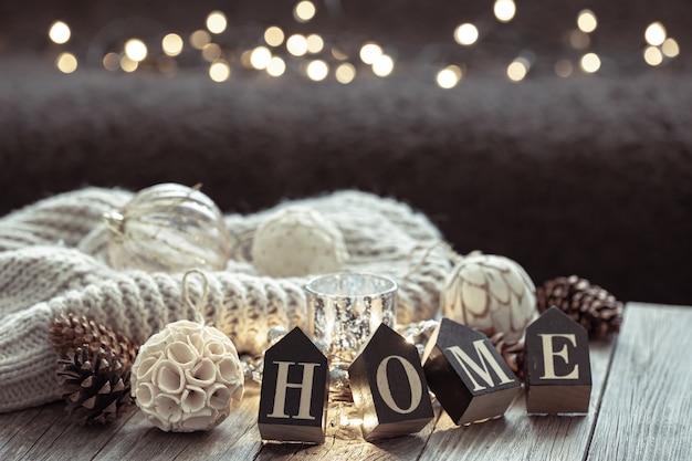 Close up of wooden letters make the word home, details of Christmas decor on blurred background with bokeh.