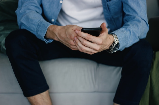 Close-up of a young man using the phone at home.