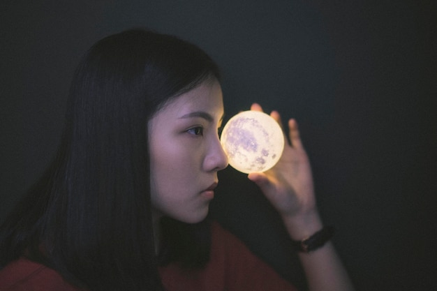 Photo close-up of young woman holding illuminated crystal ball