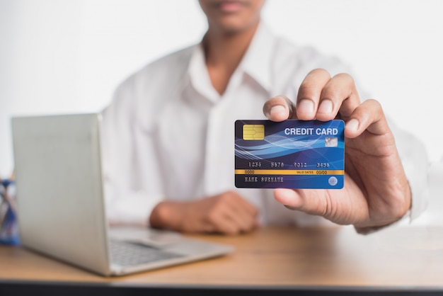 Closeup of blue credit card holded by hand. Focus on card. Online shopping concepts.