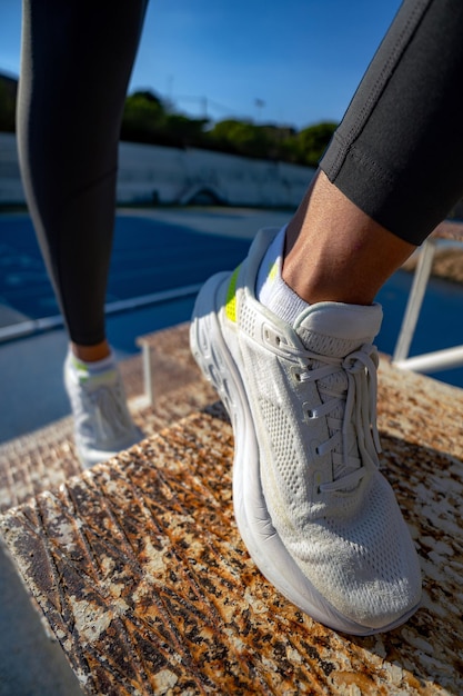 Photo closeup detail of the white running shoes of an athletic woman climbing some rusty iron stairs