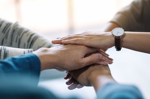 Closeup image of people putting their hands in stack together