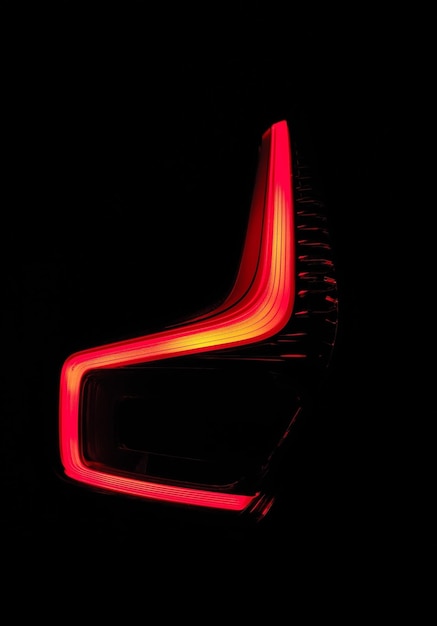 Closeup of a lit red tail light of a car against a dark background