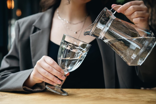 Closeup a woman pours water into a glass in a cafe