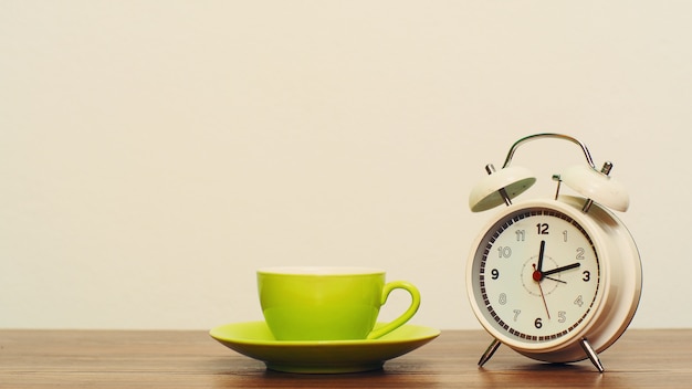 Coffee cup with white clock on wood, coffee break