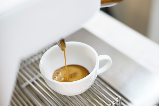 Photo coffee machine making black coffee and pouring into a cup at cafe