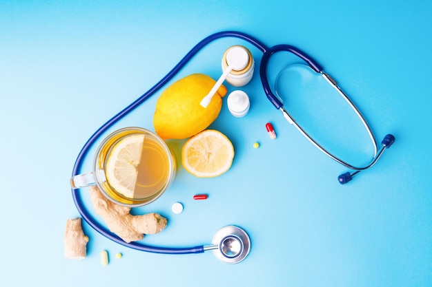 Cold preparations stethoscope tea lemon and ginger root on a blue background