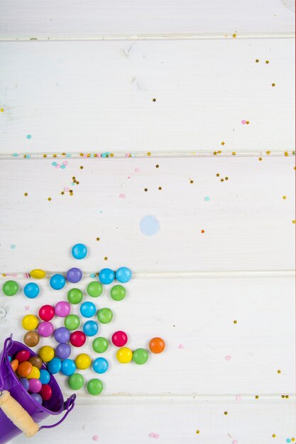 Colored candy bonbons scattered on white wooden board surface Studio Photo