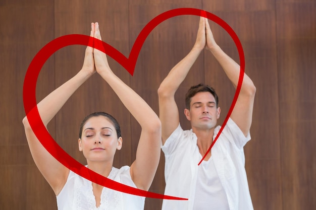 Composite image of peaceful couple in white doing yoga together with hands raised