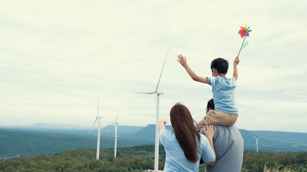Photo concept of progressive happy family enjoying their time at the wind turbine farm electric generator from wind by wind turbine generator on the country side with hill and mountain on the horizon