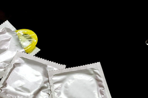 Photo condom in silver packages and one opened crops and do copy space isolate on black background