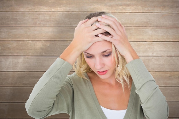 Confused young blonde with hands on head against wooden surface with planks