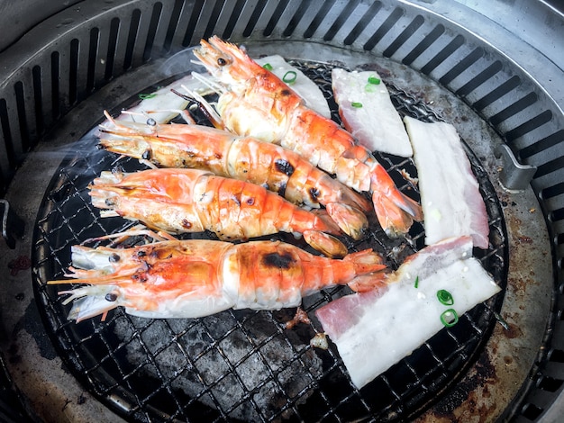 Cooking grilled shrimp with oven charcoal grill by grilled on steel grating. Below is the charcoal that is very hot.