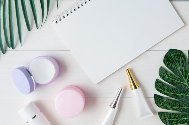 Cosmetic and skin care product and notebook and leaves on table