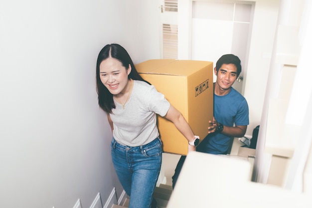 Photo couple carrying heavy moving boxes together.