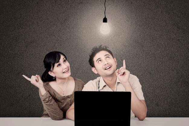 Photo couple looking at lit light bulb and laptop