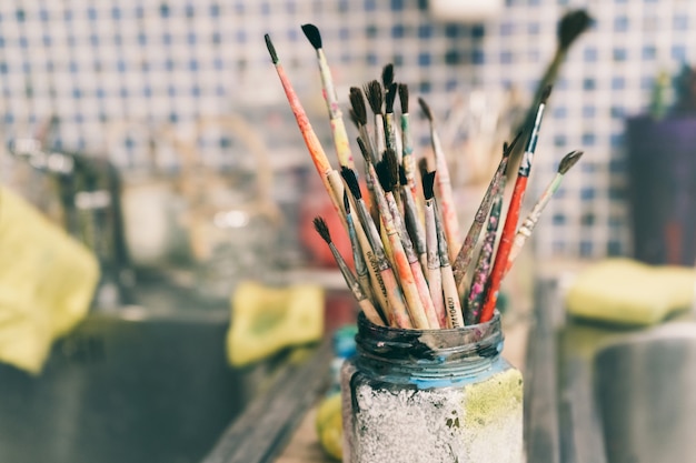 Creative workshop of the artist. Paint brushes in a jar. Many brushes for painting in one place