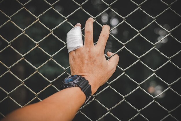 Foto mano tagliata di un uomo che tiene una recinzione a catena